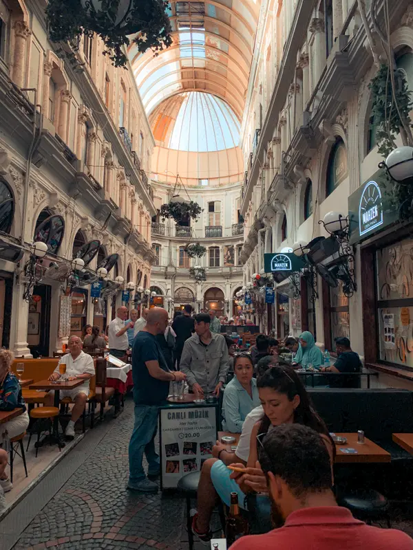 Historic covered passage with glass dome ceiling and diners in Istanbul — Aziz Stiti travel photography