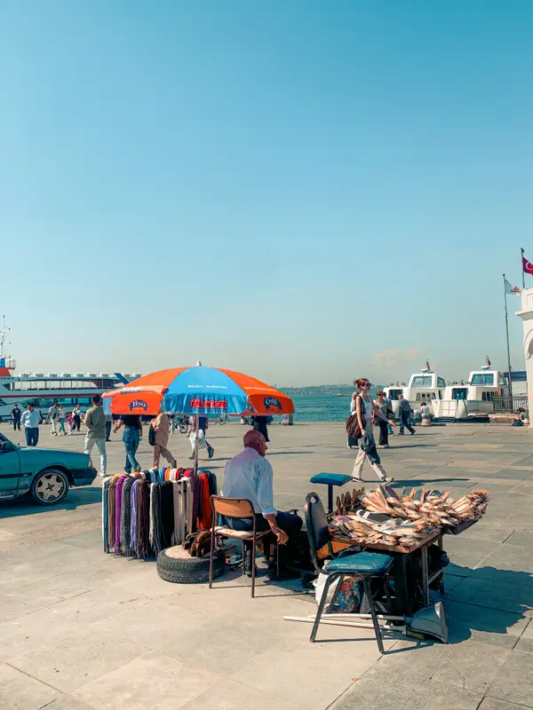 Street vendor with colorful umbrellas at Istanbul waterfront with ferries — Aziz Stiti travel photography