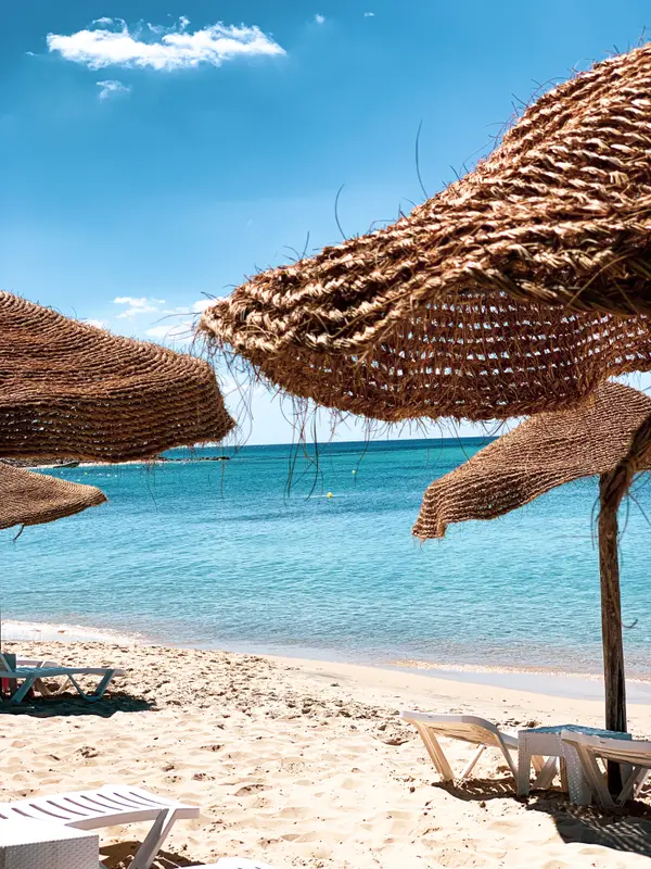 Straw parasols and sun loungers on a turquoise beach in Tunisia — Aziz Stiti photography