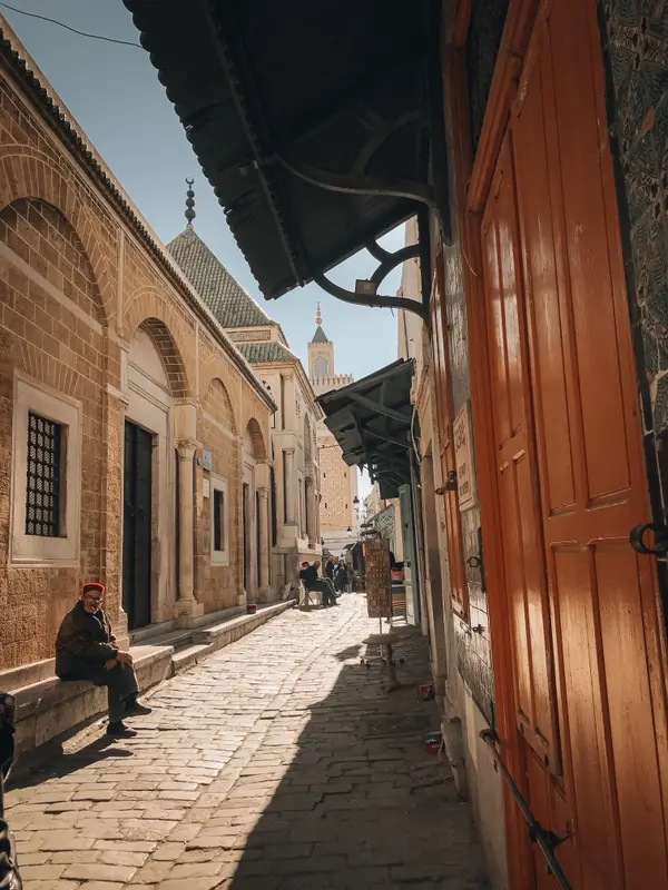 Narrow alley in Tunis Medina with old man sitting by traditional doorways — Aziz Stiti street photography