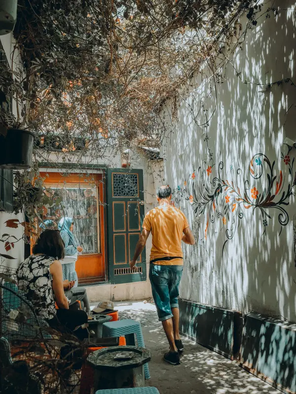 Colorful courtyard with street art mural and a man walking through — Aziz Stiti urban photography
