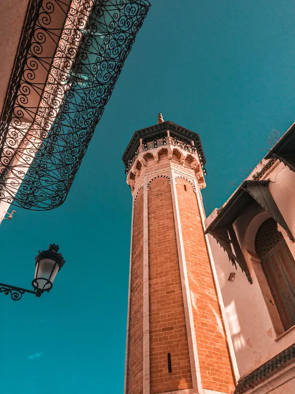 Brick minaret with ornate iron balcony shot from below against blue sky in Tunisia — Aziz Stiti